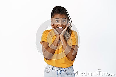 Joyful african girl reacts to surprise news, big promo offer, looking amazed at camera, standing in yellow tshirt over Stock Photo