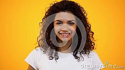 Joyful african woman smiling camera on orange background, natural beauty, youth Stock Photo