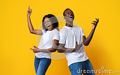 Joyful black man and woman dancing and singing on yellow Stock Photo