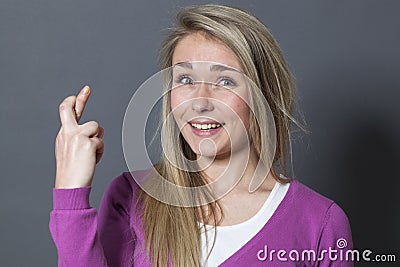 Joyful blond girl trusting faith in crossing her fingers tight Stock Photo