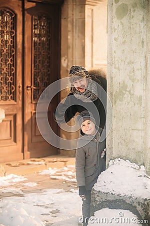 A joyful boy in a coat is playing with father in winter Stock Photo