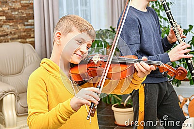 A joyful boy plays a musical composition on the violin, accompanied by a piano Stock Photo