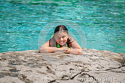 Joyful child girl lying and relaxing on the edge of the cliff against gorgeous amazing Cyprus lake background Stock Photo