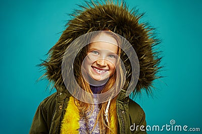 Joyful children girl in demi season winter jacket isolated on blue background. Smiling teenage child expresses sincere Stock Photo