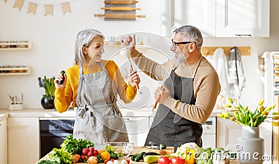 Joyful elderly couple have fun dancing and singing while cooking together in kitchen Stock Photo