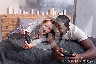 Joyful couple playing video games in bed Stock Photo