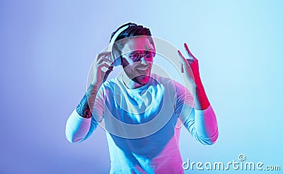 Joyful emotion concept. Guy in headphones dances to favorite music and shows cool sign Stock Photo