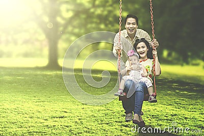 Joyful family playing on swing Stock Photo