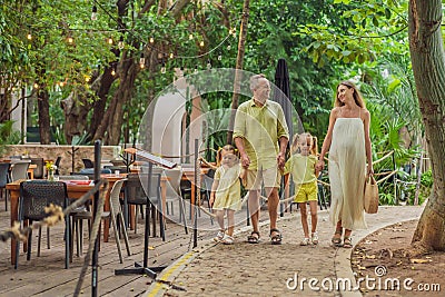 A joyful family, two girls, dad, and a pregnant mom, bask in tropical resort, celebrating a radiant pregnancy amidst Stock Photo