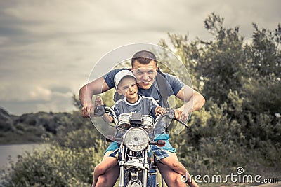 Joyful father biker son riding motorcycle lifestyle portrait concept happy paternity Stock Photo