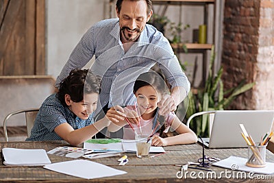 Joyful father and his children washing brushes in a glass Stock Photo