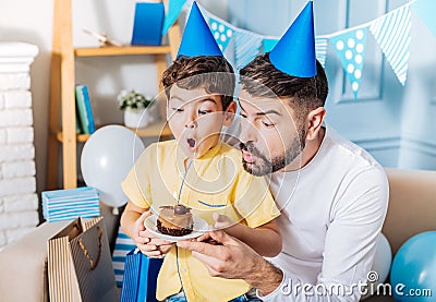 Joyful father and son enthusiastically blowing out birthday candle Stock Photo