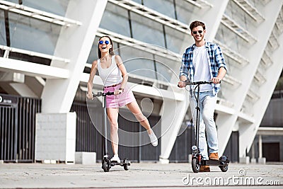 Joyful friends riding a kick scooter. Stock Photo