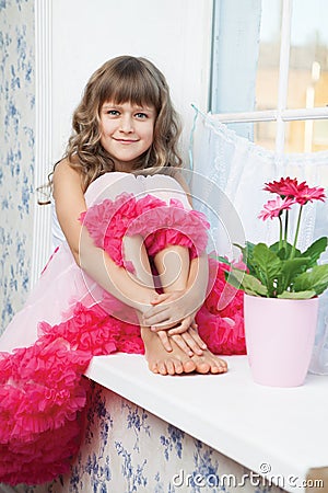 Joyful girl teenager sitting on windowsil in room Stock Photo