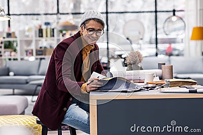 Joyful good-appealing adult fancy designer selecting fabric samples in office Stock Photo