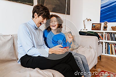 Joyful grandmother and grandson playing games on smartphone together at home Stock Photo