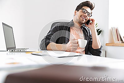 Joyful handsome man in eyeglasses talking by smartphone Stock Photo