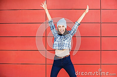 Joyful happy young woman jumping against red wall. Excited beautiful girl portrait Stock Photo