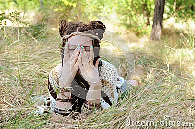 Joyful indie style woman with dreadlocks hairstyle, have a fun closing her face with a hands Stock Photo