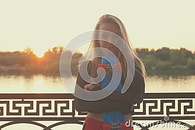 Joyful lady posing holding her pennyboad in front of her body Stock Photo