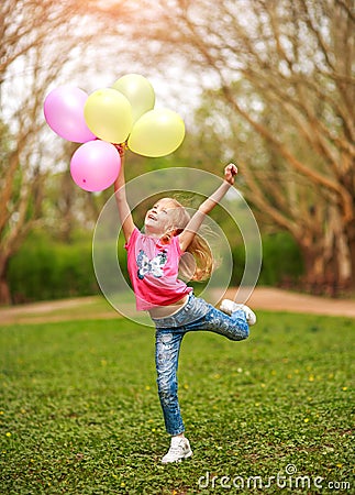Joyful little girl child jumping from happiness in spring green park Stock Photo