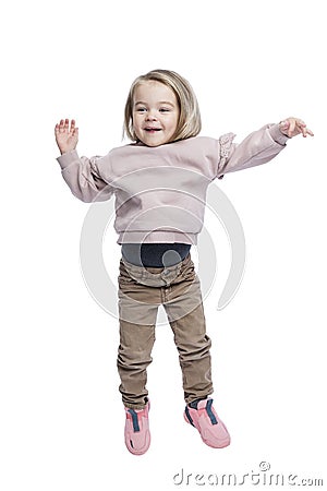 Joyful little girl is jumping. Cute baby in pink sweater, brown pants and sneakers. Positivity and happiness. Isolated on white Stock Photo