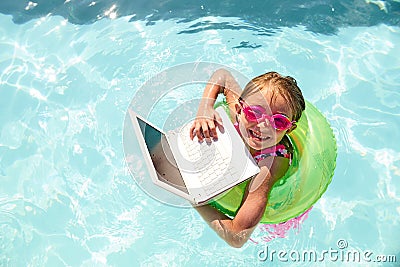 Joyful little girl swimming in pool with laptop Stock Photo