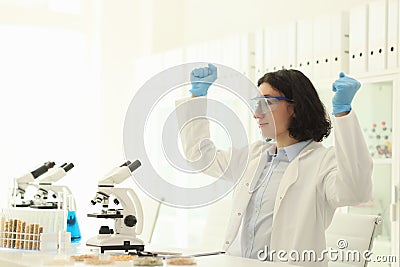 Joyful male scientist in protective goggles raises hands Stock Photo