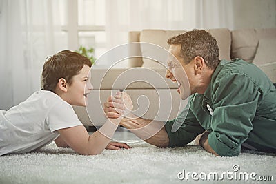 Cheerful father and son playing arm-wrestling at home Stock Photo