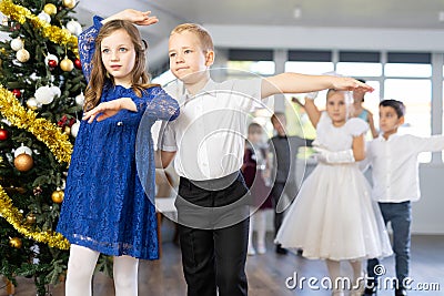 Little children practicing waltz dance in school-hall decorated with Christmas-tree Stock Photo