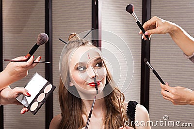 Joyful model surrounded by hands holding brushes Stock Photo