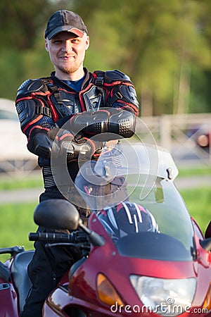 Joyful motorcyclist standing on his bike. Safety equipment as protector jacket Stock Photo