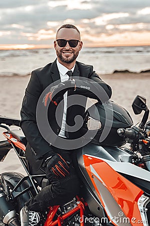 Joyful motorcyclist in suit riding sports bike on beach Stock Photo