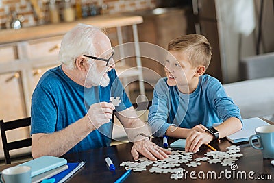 Joyful nice man collecting jigsaw puzzles Stock Photo