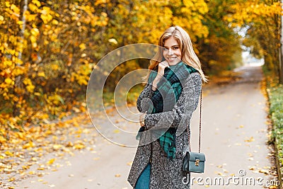 Joyful pretty young happy woman in stylish warm seasonal clothes with a leather handbag is standing and smiling on the road Stock Photo