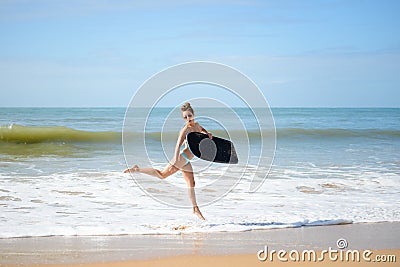 Joyful surfer girl happy cheerful running surfing at ocean beach water. Female bikini heading for waves with surfboard Stock Photo