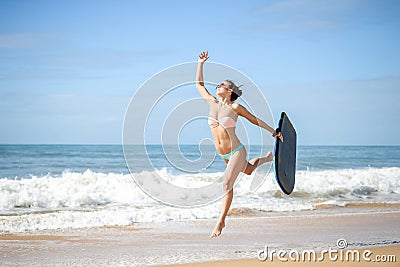 Joyful surfer girl happy cheerful running surfing at ocean beach water. Female bikini heading for waves with surfboard Stock Photo