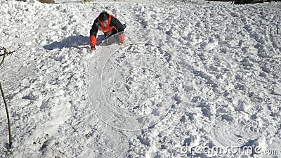 Joyful teen playing sliding in the snow in a sunny winter day at the mountain stock video footage Joyful teen playing sliding in the snow in a sunny winter day at the mountain stock video footage