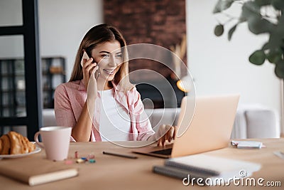 Joyful woman having a phonecall and checking updates on laptop Stock Photo