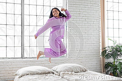 Joyful woman jumping on bed at home Stock Photo