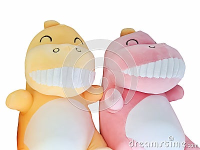 A joyful yellow and pink dinosaur doll smiles wide with split teeth on a white background Stock Photo