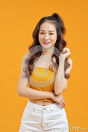 Joyful young asian woman in yellow crop top posing isolated on yellow background Stock Photo