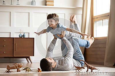 Joyful young man father lifting excited happy little son. Stock Photo