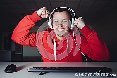 Joyful young man with headphones at home playing a computer game. Gamer happy for the win. Stock Photo