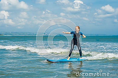 Joyful young woman beginner surfer with blue surf has fun on small sea waves. Active family lifestyle, people outdoor Stock Photo