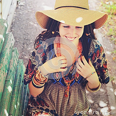 Joyful young woman portrait with dreadlocks dressed in boho style dress and necklace, sunny outdoor Stock Photo