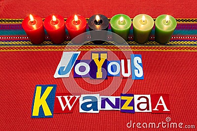 JOYOUS KWANZAA text word collage typography, with seven candles and multi colored fabric on red woven fabric, African American hol Stock Photo