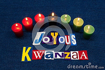 JOYOUS KWANZAA word text collage typography, seven candles and multi colored fabric on blue denim, African American holiday Stock Photo