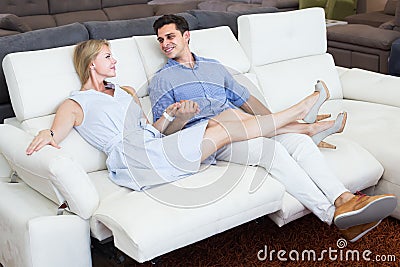 Joyous man and woman are choosing of sofa-transformer in furniture store Stock Photo