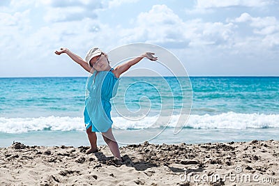 Joyous young girl with hands up relaxing on sandy beach Stock Photo